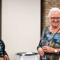 Three women talking by tables